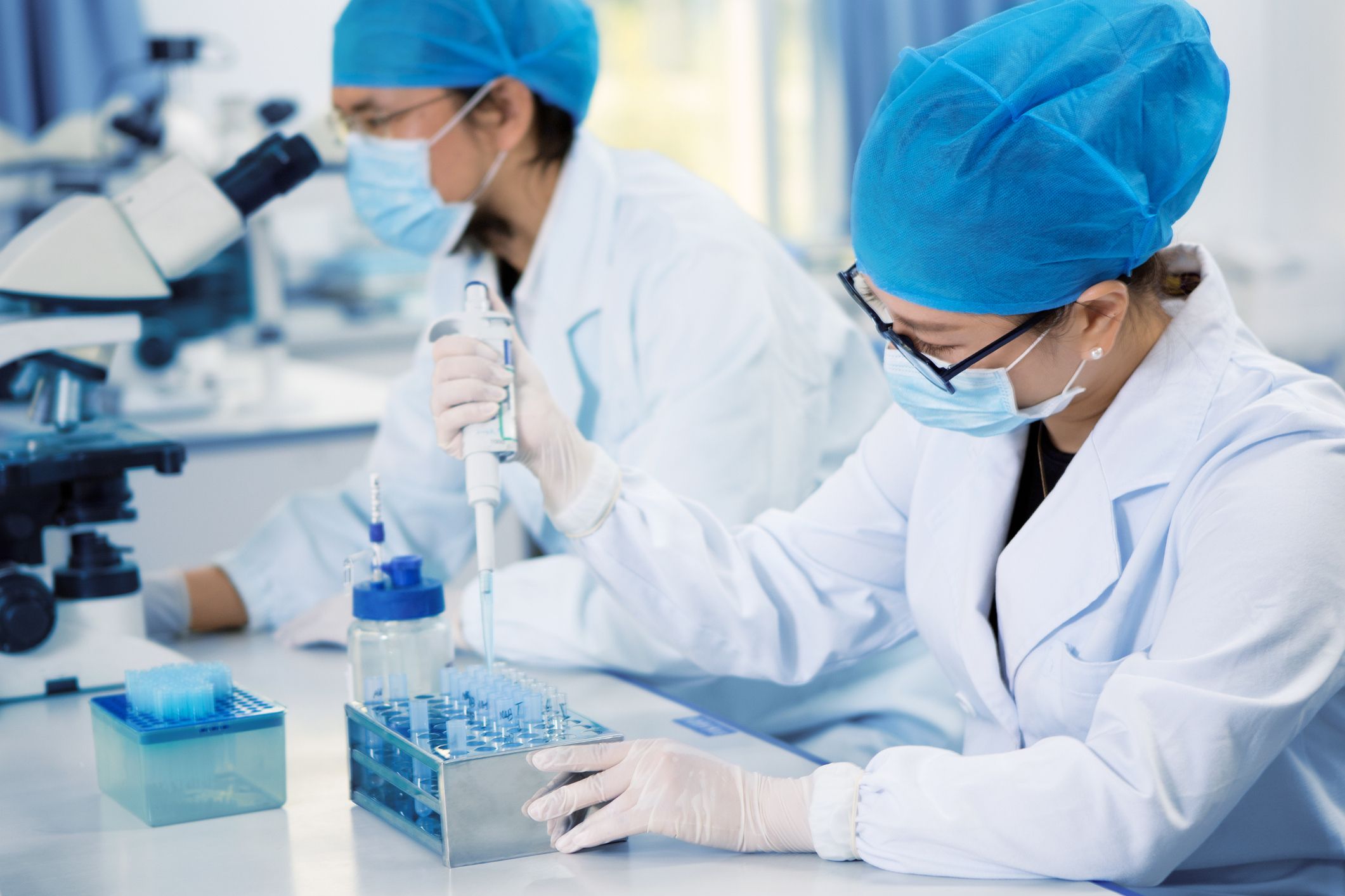 Researchers performing tasks with pippette and microscope.